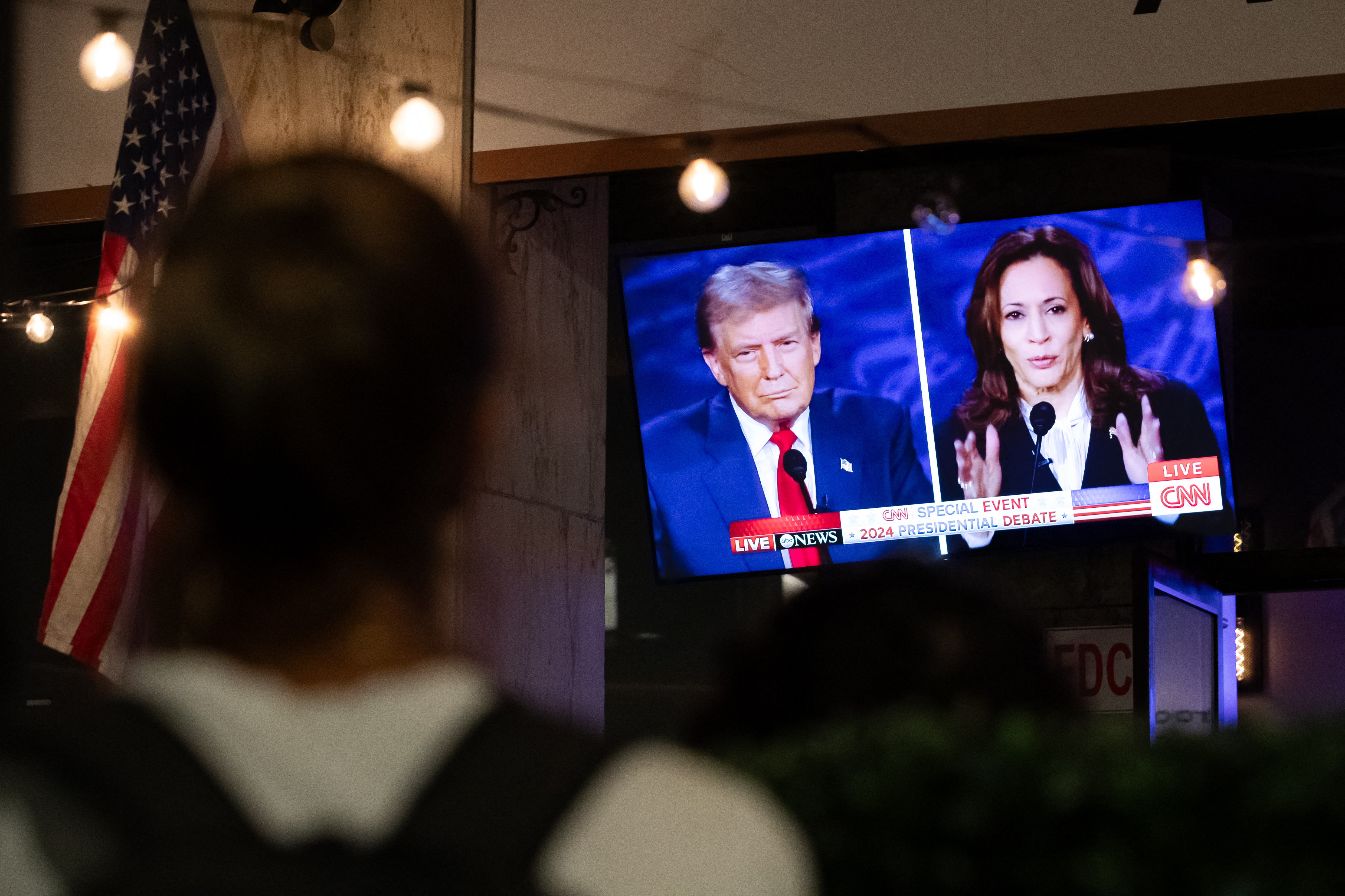 Two candidates for the US presidency. A person stops to watch a screen displaying the US Presidential debate between Vice President and Democratic presidential candidate Kamala Harris and former US president and Republican presidential candidate Donald Trump in Washington, DC, on September 10, 2024. (Photo by Allison Bailey / AFP)